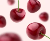 Red cherries with stems arranged on a light pink background.