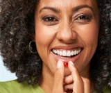 Smiling person holding a red capsule near their mouth.