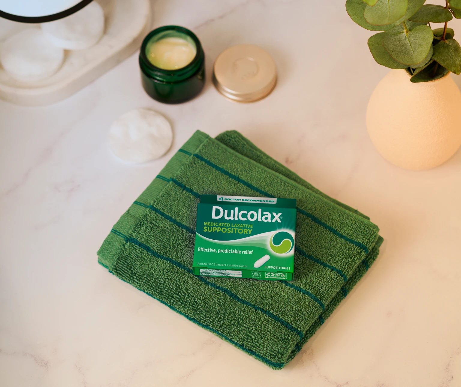 Dulcolax Medicated Laxative Suppository box on a green towel beside a jar and vase.
